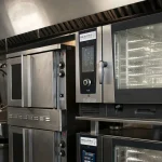 Commercial catering gas appliances, combi ovens, and mechanical extraction canopy in a London restaurant kitchen